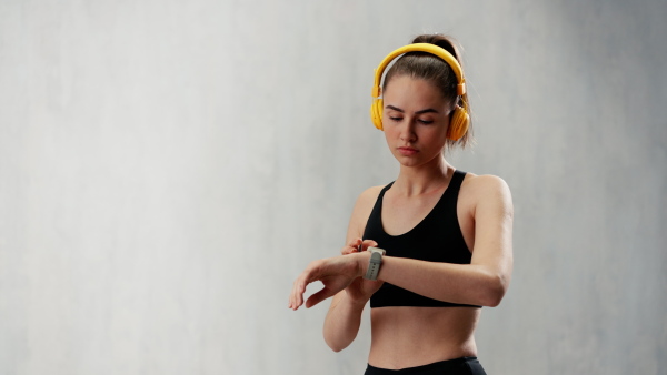 A fitness woman relaxing and listening music during her workout over grey background.