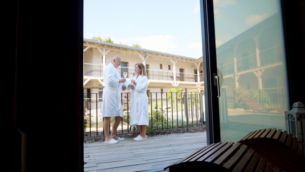 A side view of senior couple enjoying their vacation in spa resort, talking on terrace.