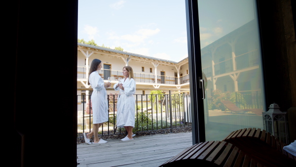 A side view of mature female friends enjoying their vacation in spa resort, talking on terrace.