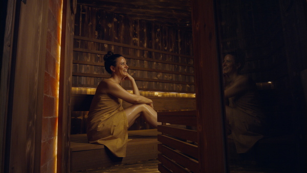 A mature woman enjoying her vacation in spa resort, sitting in sauna and looking at camera.