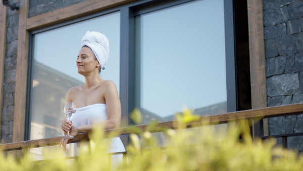 A mature woman enjoying her vacation in spa resort, standing on terrace and looking at camera.