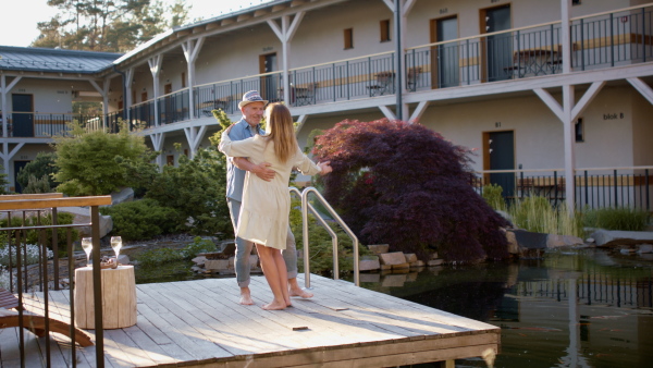 A senior couple enjoying their vacation in spa resort, dancing on terrace.