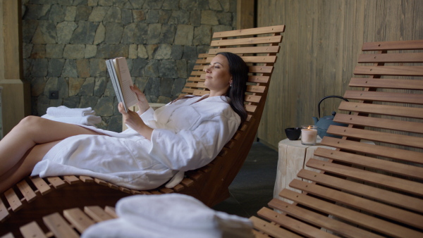 A mature woman enjoying her vacation in spa resort, reading a book.