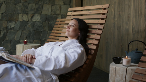 A mature woman enjoying her vacation in spa resort, reading a book and looking at camera..