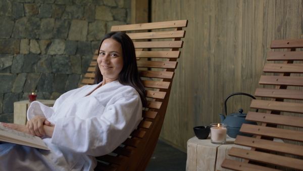 A mature woman enjoying her vacation in spa resort, reading a book and looking at camera..