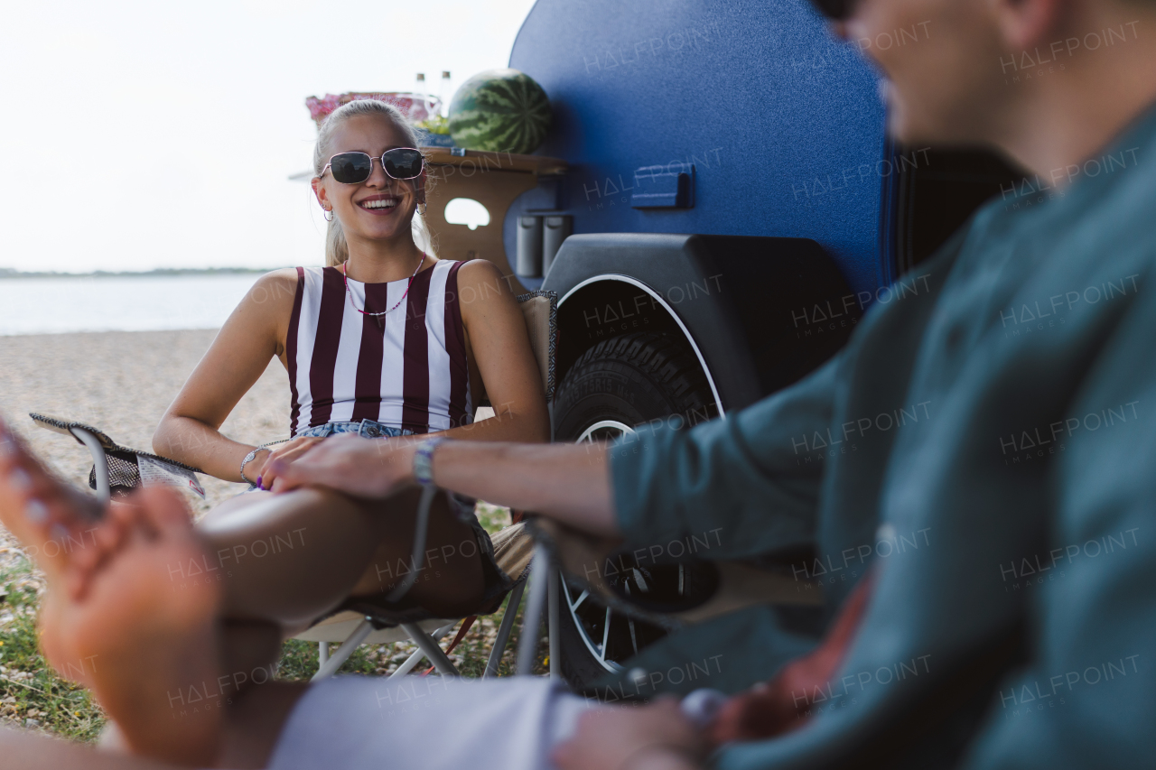 A young couple sitting together in front of van during summer vacation, bonding.