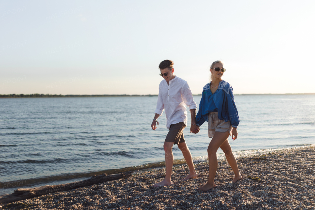 Happy young couple walking on a beach during sunset, prepairing for a picnic.