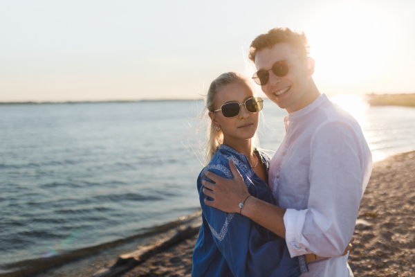 Young cupple cuddling during sunset at lake.