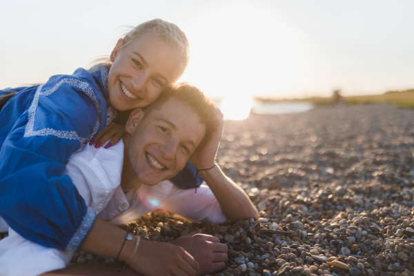 A happy young woman lying on her boyfriends back, looking at camera, having fun together.