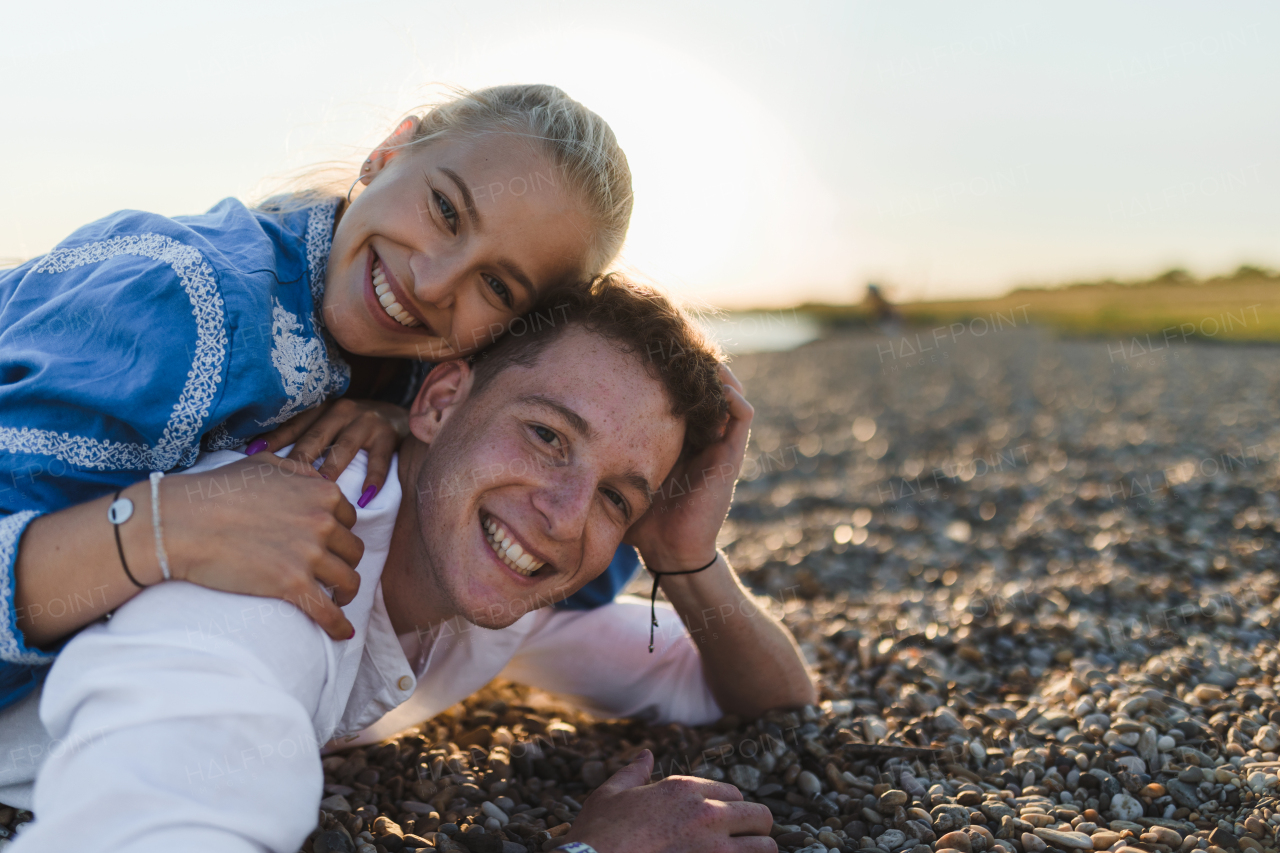 A happy young woman lying on her boyfriends back, looking at camera, having fun together.