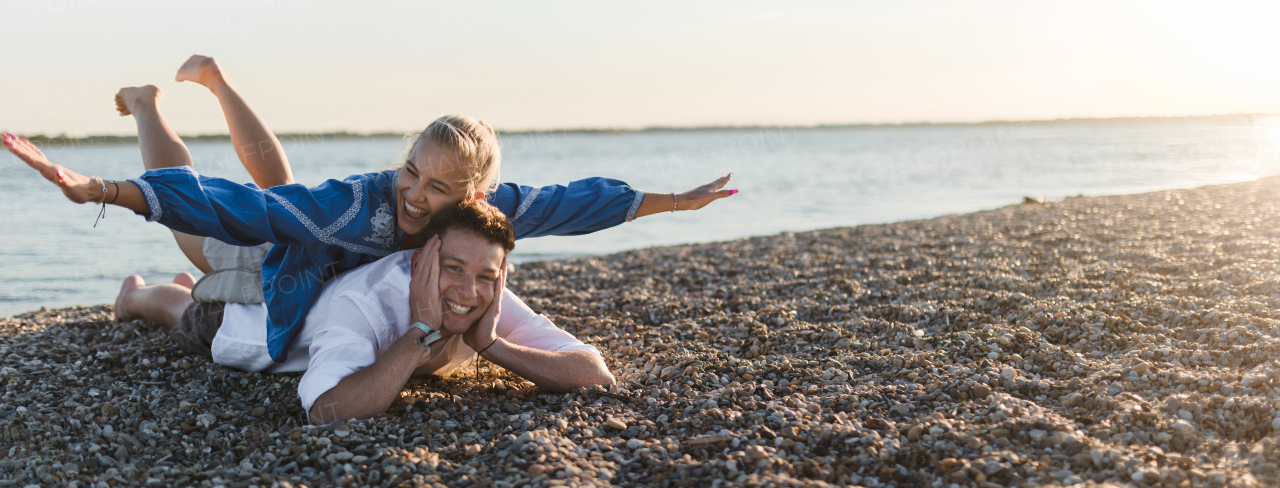 A happy young woman lying on her boyfriends back, looking at camera, having fun together. Wide photography.