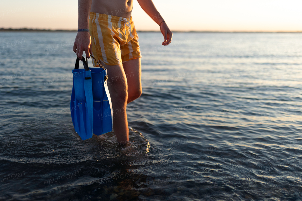 Low section of man in swimsuit with swimmers fins.