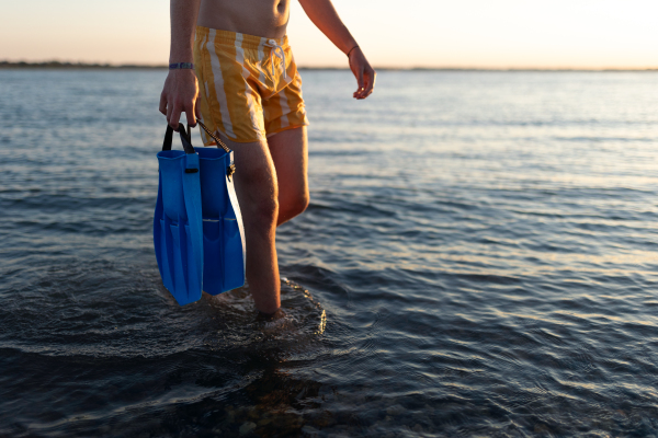 Low section of man in swimsuit with swimmers fins.