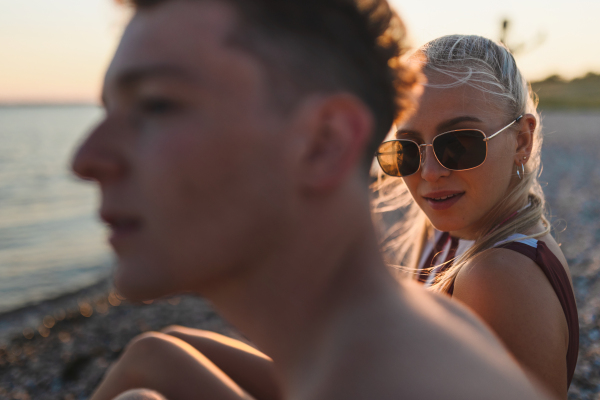 Young couple spending time at lake, during sunset.