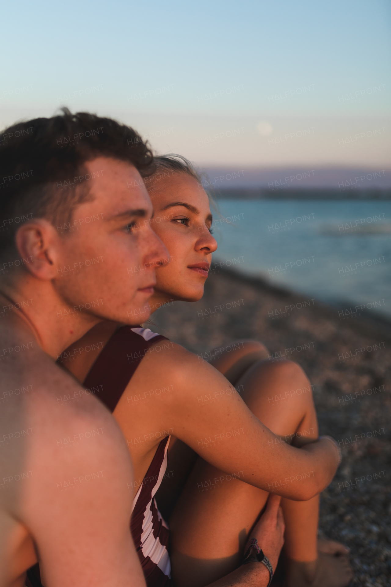 Young couple spending time at lake, during sunset.