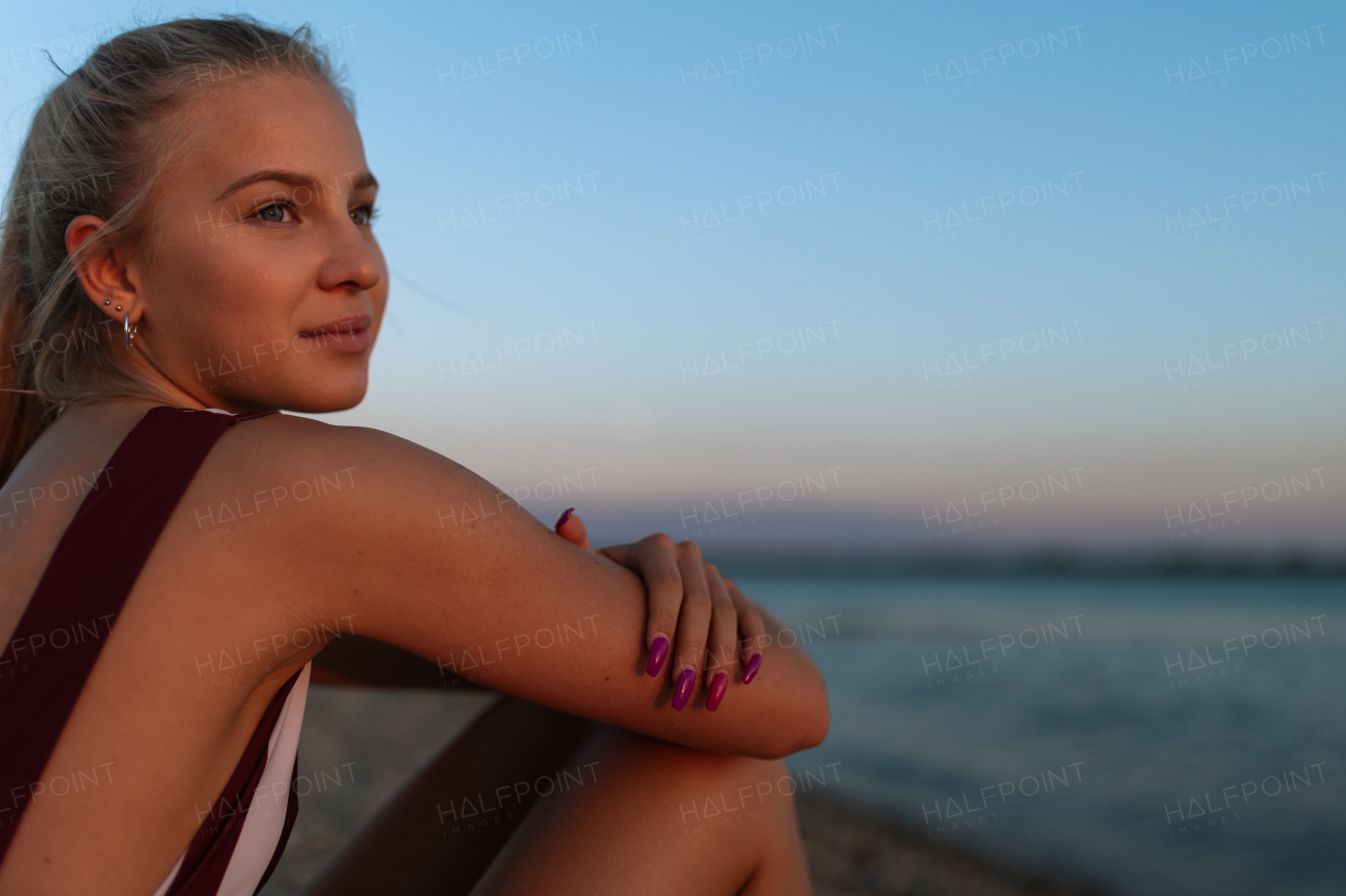 A young woman in swimsuit sitting on beach alone, summer vacation concept.