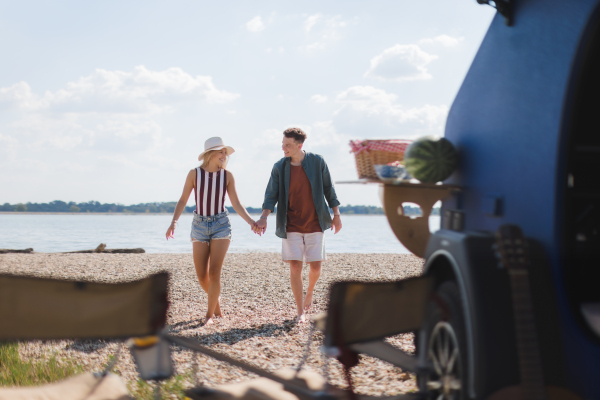 Young couple in front of van during summer holiday.