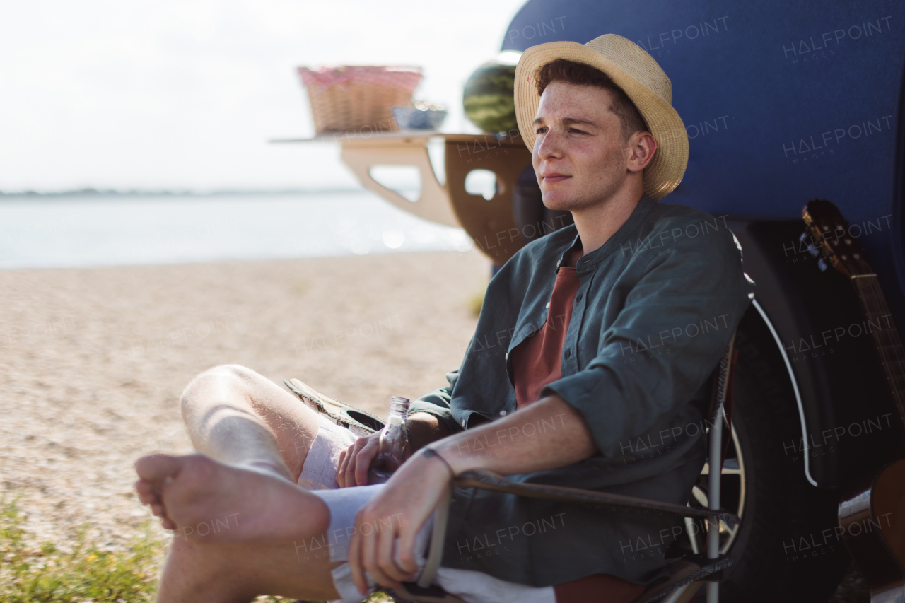 Young man sitting in front of a van enjoying summer time.