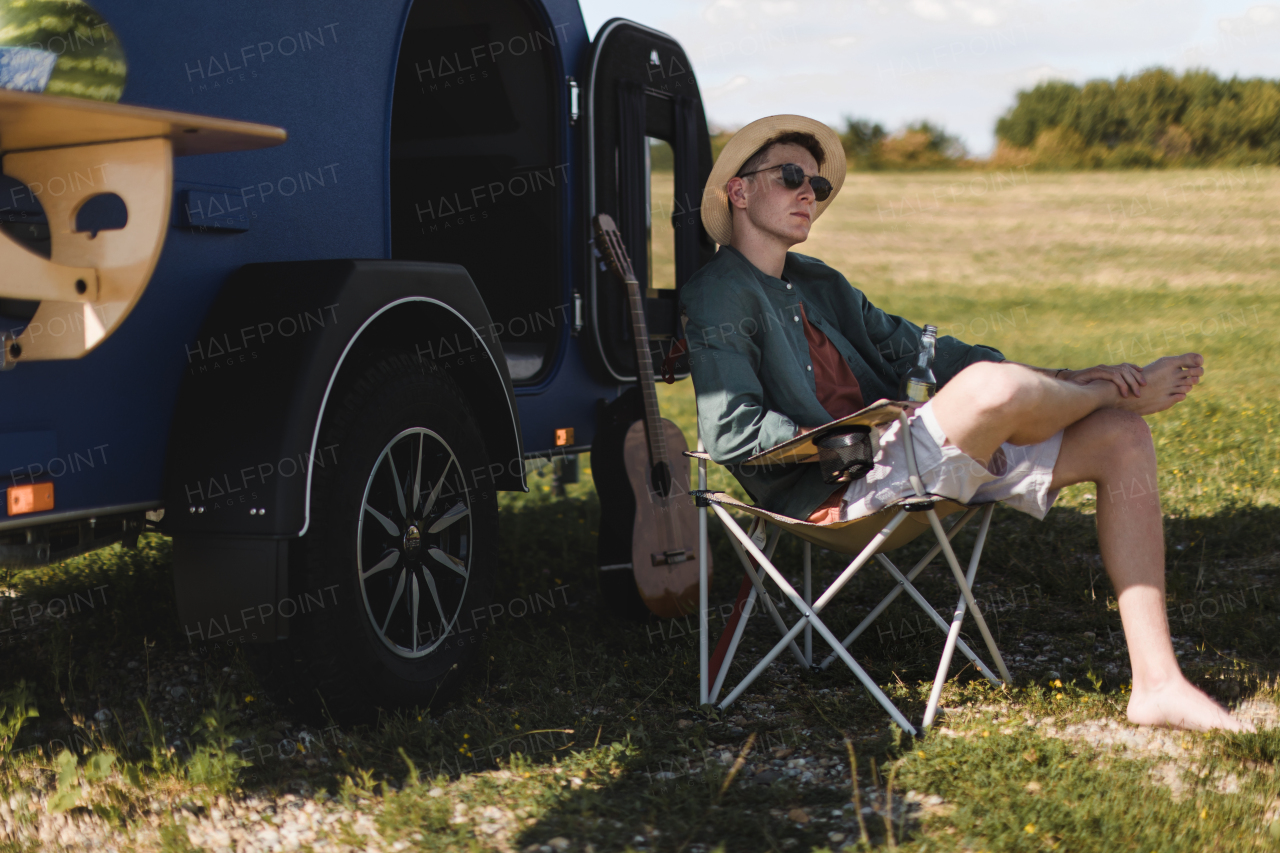 Young man sitting in front of a van enjoying summer time.