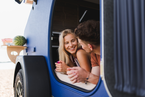 Happy young couple lying together in the van, enjoying vacation time together.