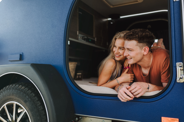 Happy young couple lying together in the van, enjoying vacation time together.