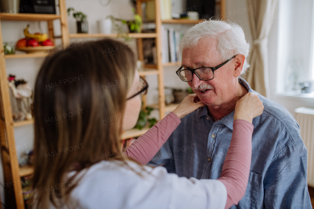 A healthcare worker or caregiver visiting senior man indoors at home.