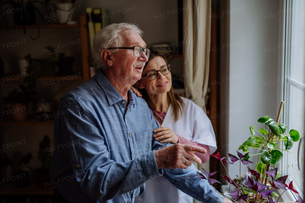 A healthcare worker or caregiver visiting senior man indoors at home, talking.