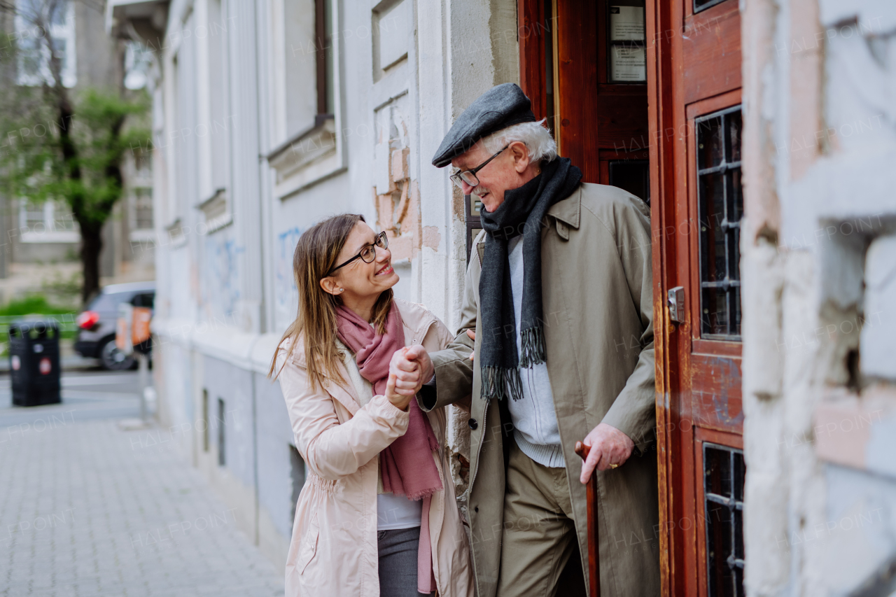 An adult daughter taking her senior man for a walk in town.