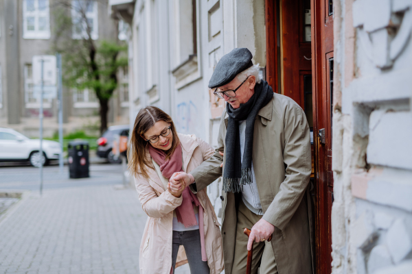 An adult daughter taking her senior man for a walk in town.