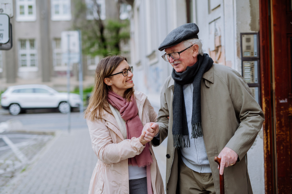 An adult daughter taking her senior man for a walk in town.