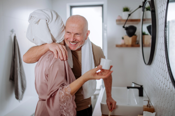 A senior couple in bathroom, brushing teeth and talking, morning routine concept.