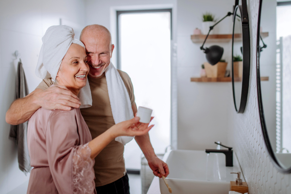 A senior couple in bathroom, brushing teeth and talking, morning routine concept.