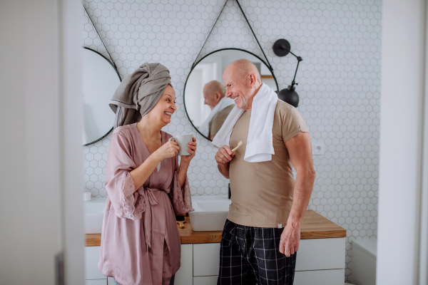 A senior couple in bathroom, brushing teeth and talking, morning routine concept.