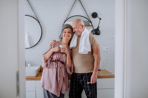 A senior couple in bathroom, brushing teeth and talking, morning routine concept.