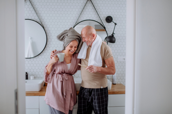 A senior couple in bathroom, brushing teeth and talking, morning routine concept.