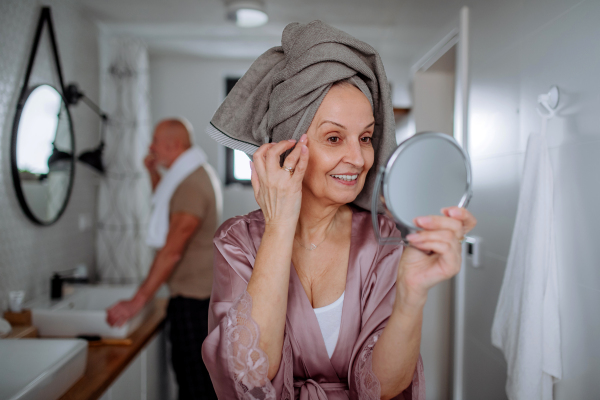 A senior couple in love in bathroom, brushing teeth and looking at camera, morning routine concept.