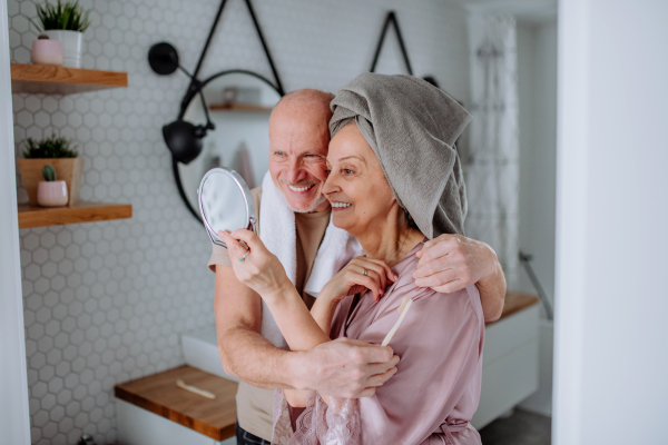 A senior couple in love in bathroom, looking at mirror and smiling, morning routine concept.