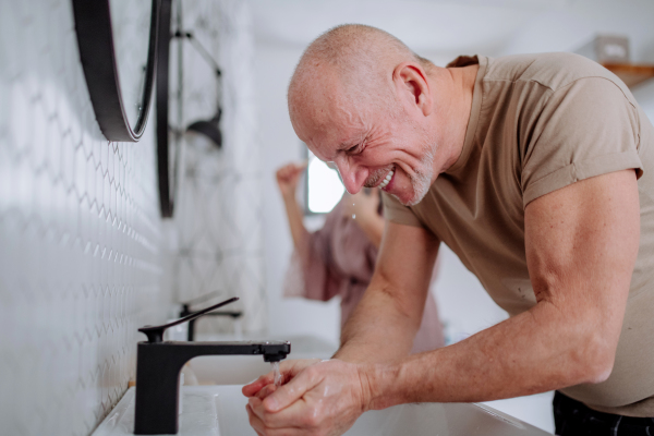 A senior couple in bathroom, brushing teeth and washing, morning routine concept.