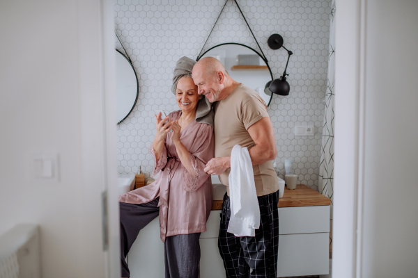 A senior couple in bathroom, useing telephone, talking and having fun, morning routine concept.