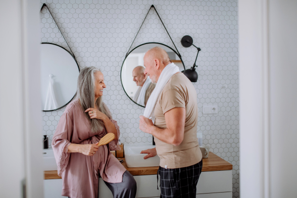 A senior couple in love in bathroom, talking, morning routine concept.