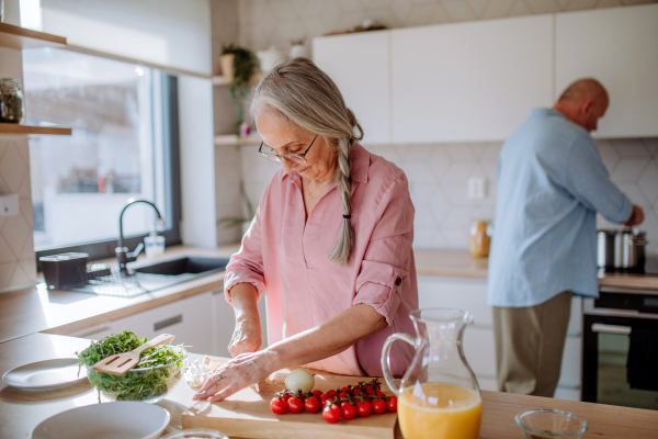 A senior couple cooking and smiling together at home.