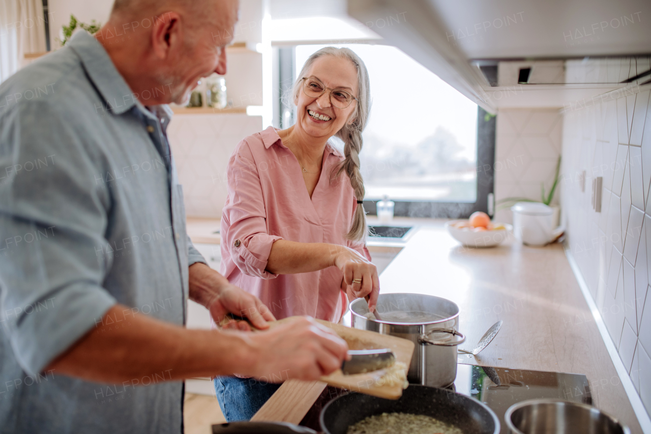 A senior couple cooking and smiling together at home.