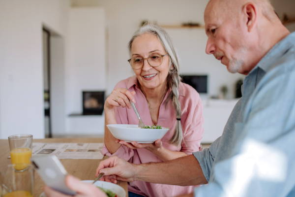 A happy senior couple eating dinner together at home.