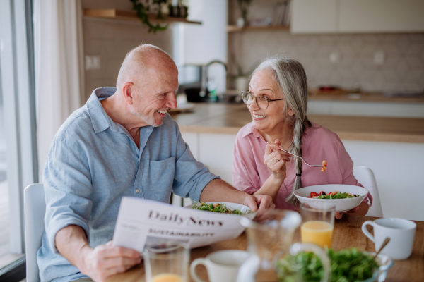 A happy senior couple eating dinner together at home.