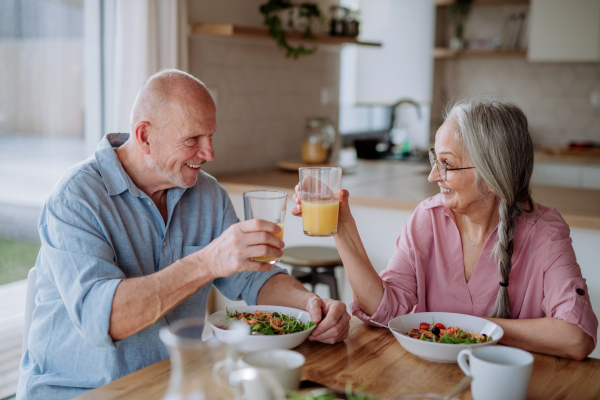 A happy senior couple eating dinner together at home.