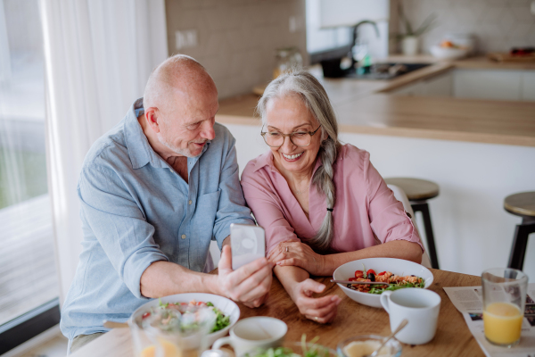 A happy senior couple eating dinner together at home.