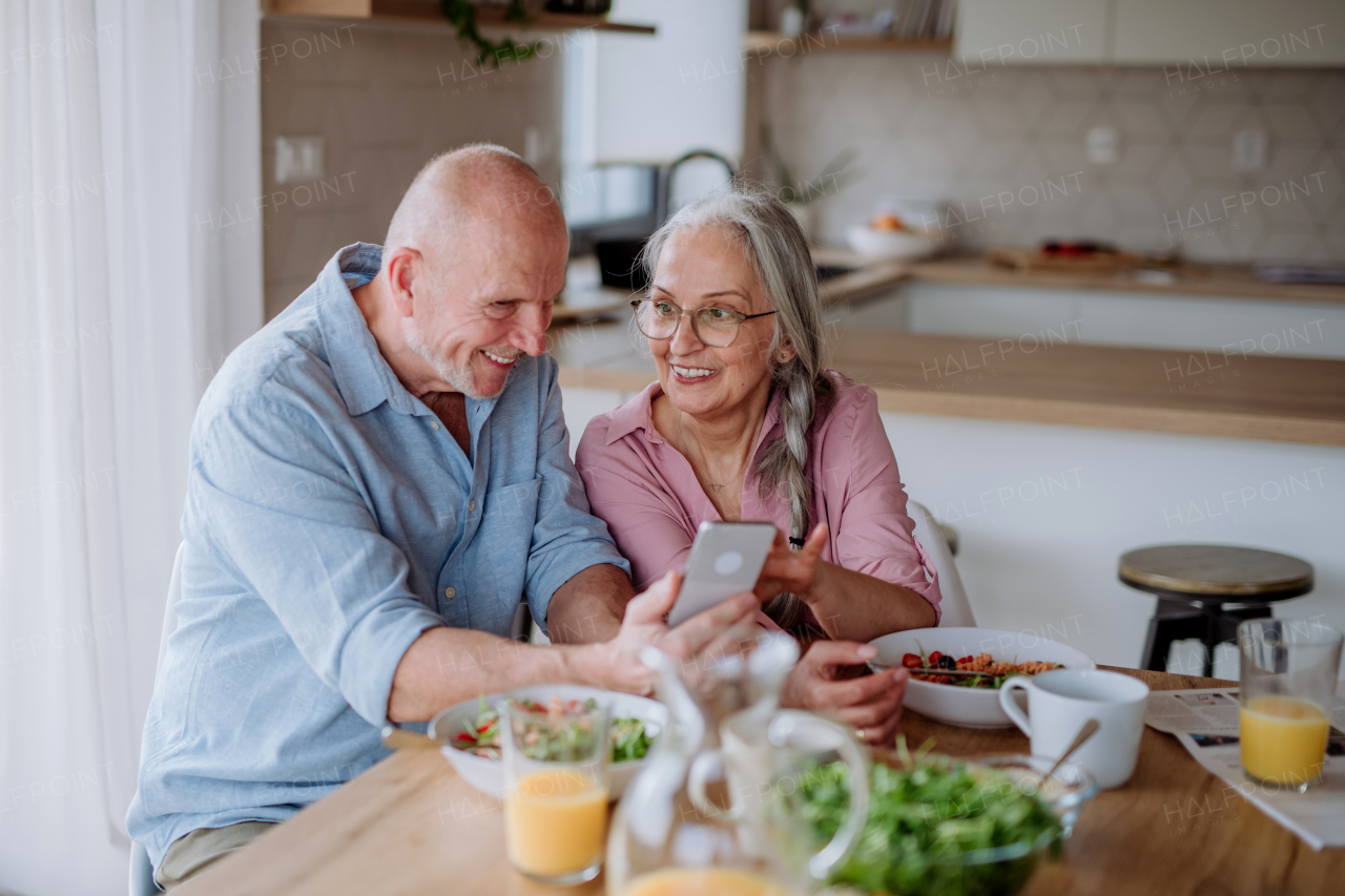 A happy senior couple eating dinner together at home.