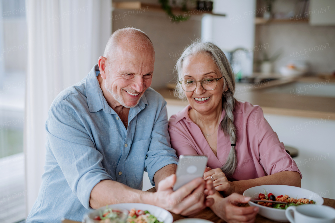 A happy senior couple eating dinner together at home.