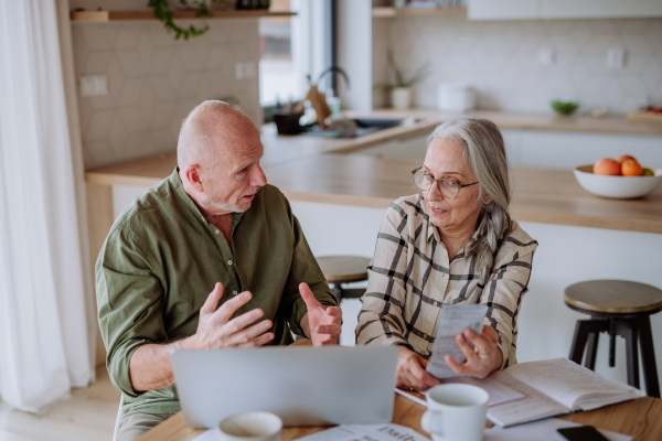 A stressed senior couple calculate expenses or planning budget together at home.