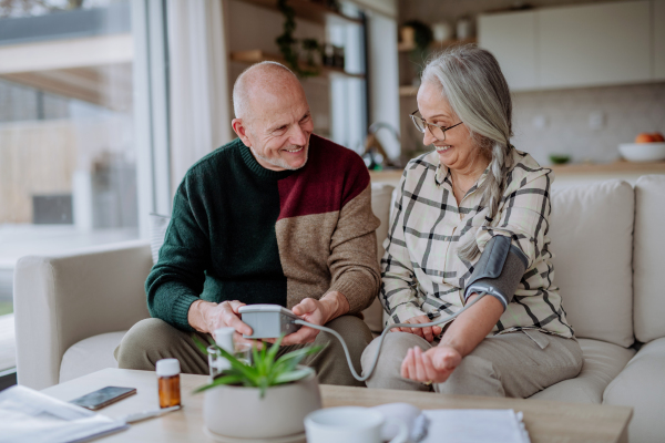 A senior couple at home measuring blood pressure.